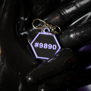 The back of a hexcorp keychain in a rubber gloved hand, number is customizable